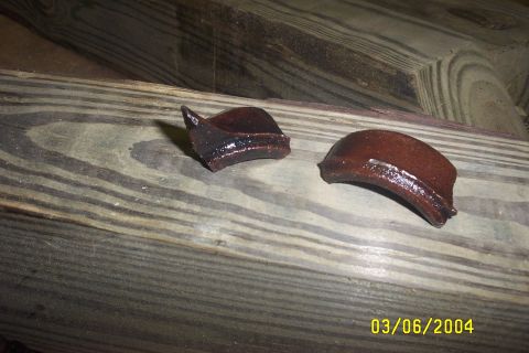 1979 Ford F-150 - Two fragments of what appears to be ceramic material are shown on a wooden surface.