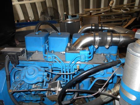 1992 Ford Bronco - Close-up of a blue engine with chrome exhaust pipes and various hoses and wiring.