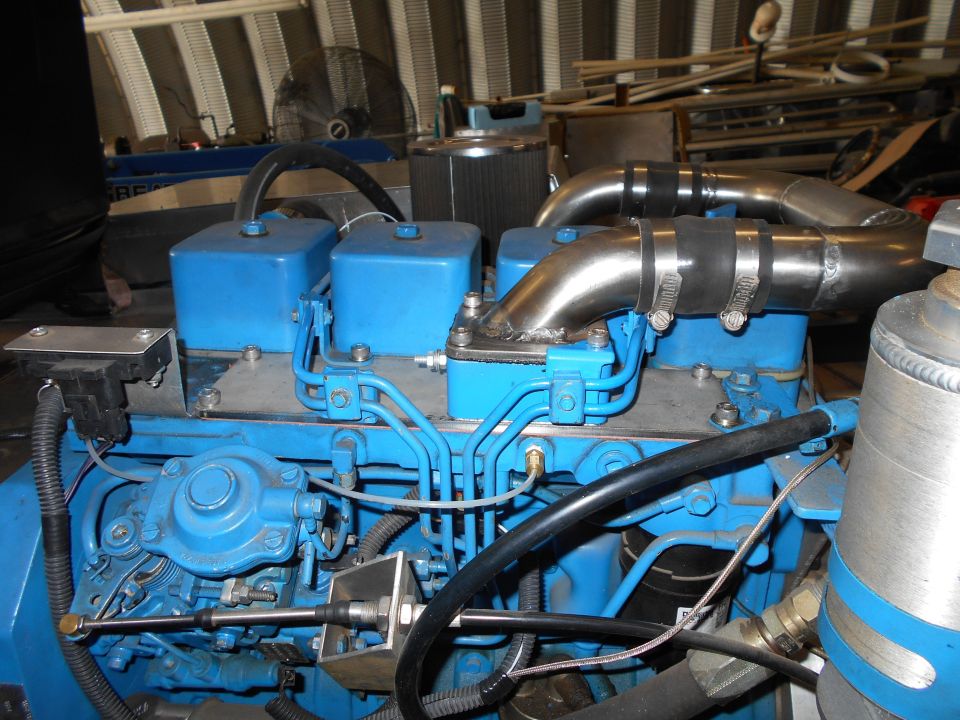 Blue engine with chrome pipes and black hoses, close-up view