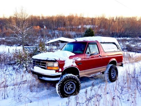 1995 Ford Bronco - Red 1995 Ford Bronco parked in a snowy field with trees in the background.