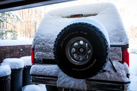 1995 Ford Bronco - A 1995 Ford Bronco is parked outside, covered in a thick layer of snow.