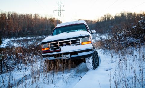 1995 Ford Bronco - A Ford truck navigates a snow-covered path, its tires kicking up snow as it drives through a winter landscape.