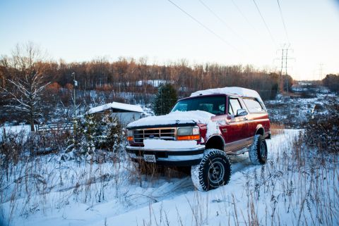1995 Ford Bronco - 1995 Ford Bronco sits in a snow-covered rural landscape during winter.