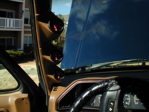 1988 Ford Bronco - Interior view of a vehicle's dashboard, showing aftermarket gauges and a steering wheel, with the hood open.
