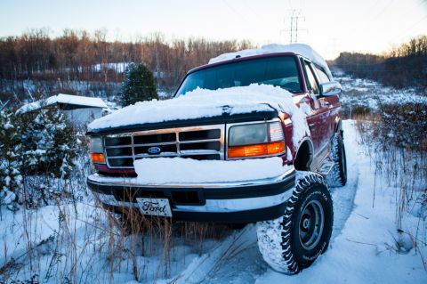 1995 Ford Bronco - A red 1995 Ford Bronco sits covered in snow, ready for winter fun.