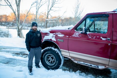 1995 Ford Bronco - A man poses with his red Ford Bronco in a snowy outdoor setting.