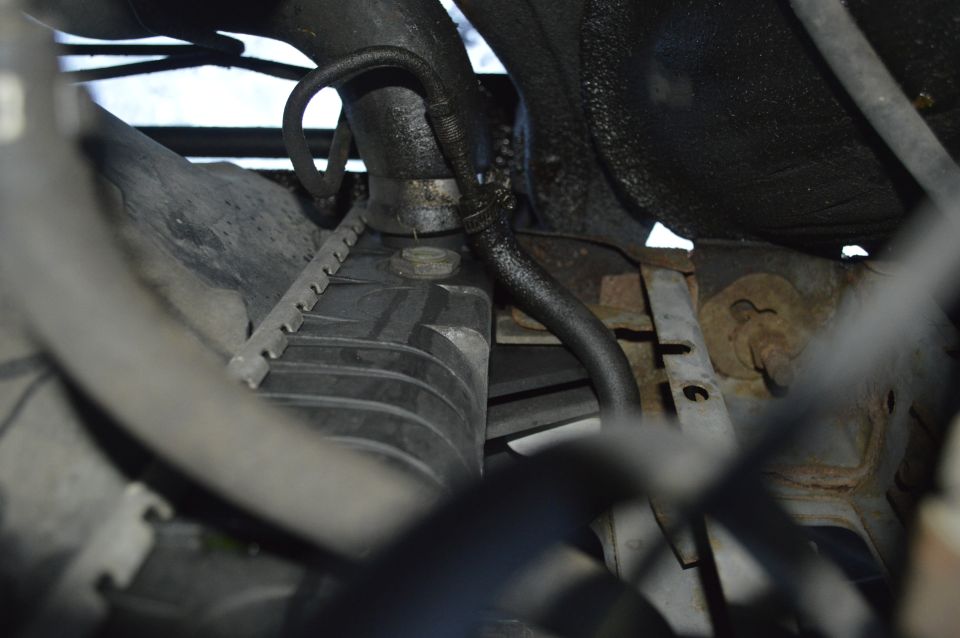 Close-up of a vehicle's radiator and hoses, showing some wear and tear