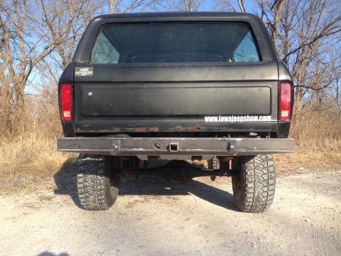 1979 Ford Bronco - The rear of a black 1978 Ford Bronco is shown with a custom bumper and large off-road tires.