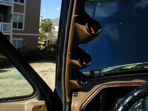 1988 Ford Bronco - Aftermarket gauges mounted on the A-pillar inside a vehicle's cabin.