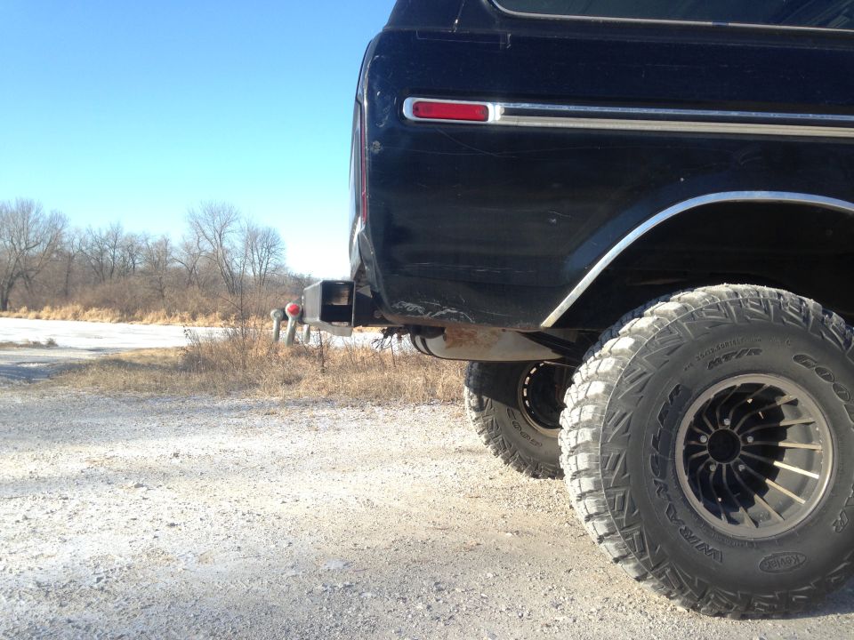 Dark SUV's rear bumper and large off-road tire. The vehicle appears to be from the late 1970s