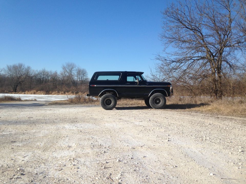 Black Ford Bronco with lifted suspension parked on a dirt road, side view
