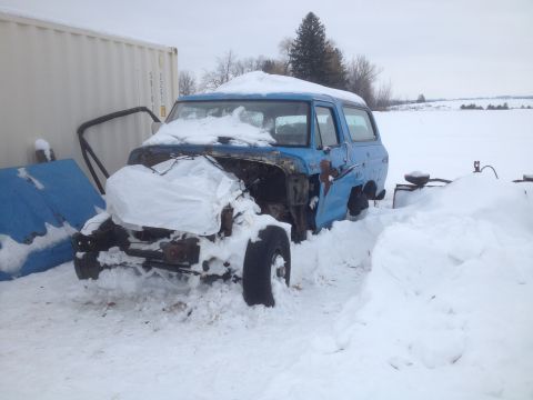 1979 Ford Bronco - A blue SUV, possibly a 1978 Ford Bronco, sits partially buried in snow with its front end exposed.