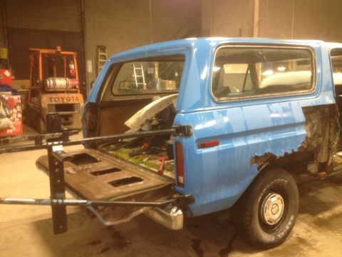 1979 Ford Bronco - This blue 1979 Ford Bronco shows significant rust on its rear quarter panel and has its tailgate open.