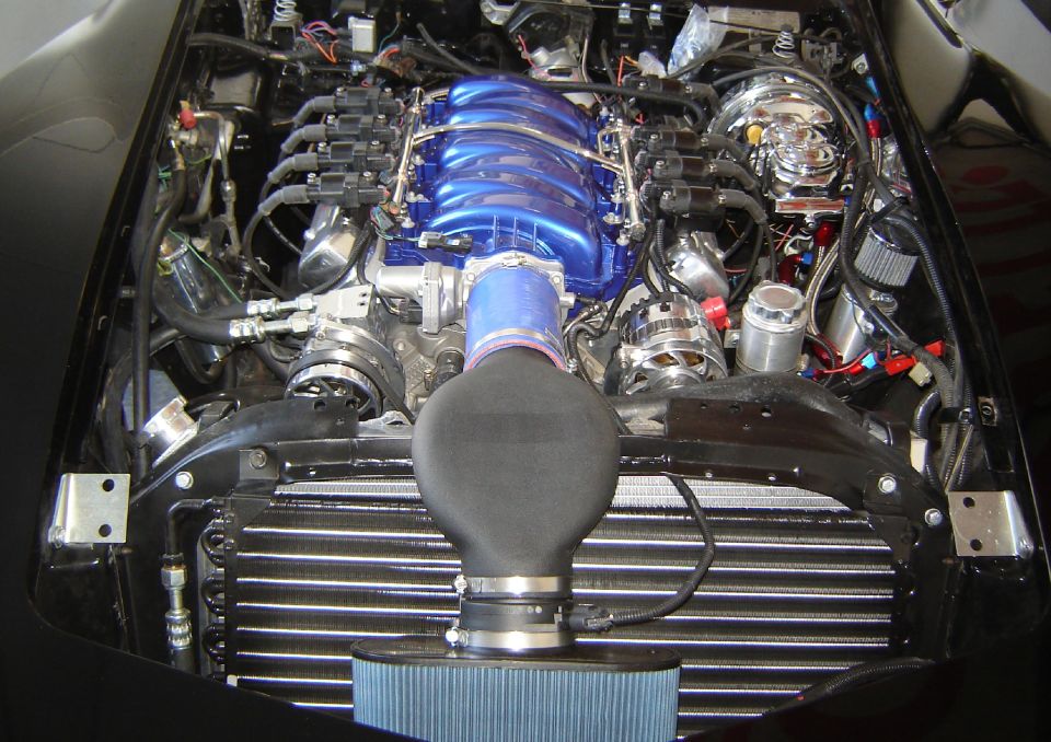 Engine bay with a shiny blue intake manifold and large air filter. Looks like a custom setup