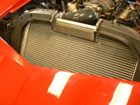 1976 Chevrolet Corvette - The engine and radiator are visible in the engine bay of a red car, with a Supermotors.net watermark.