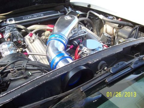 1976 Chevrolet Corvette - Engine bay details of a Corvette, a prominent chrome intake system and various engine parts.