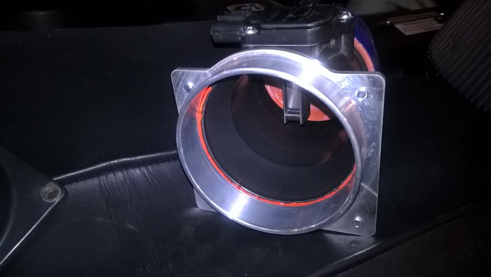 Mass air flow sensor with orange gasket on black surface