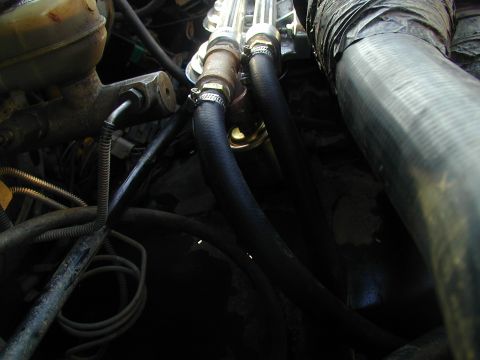 1988 Ford Bronco - This image shows a close-up view of various hoses and a fluid reservoir within a vehicle's engine compartment.