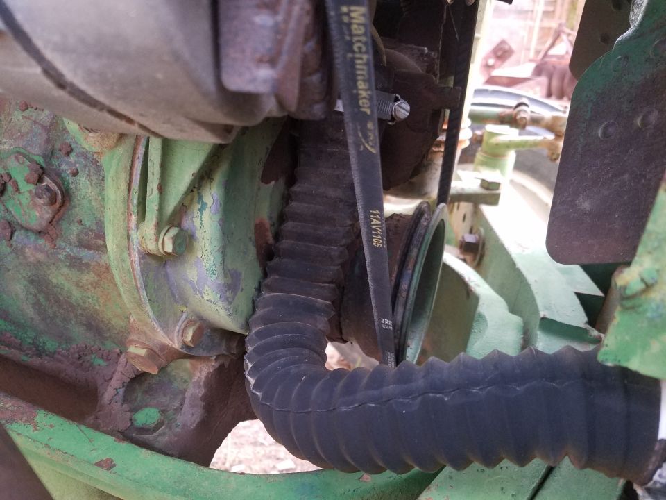 Close-up of a green tractor engine with a ribbed hose and a belt labeled 'Matchmaker'