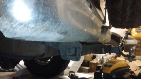 1985 Ford Bronco - The underside of a vehicle, focusing on the trailer hitch assembly and a rear tire.
