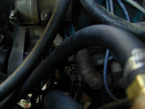 1988 Ford Bronco - Close-up view of engine components, including exhaust manifold wrap and various hoses.