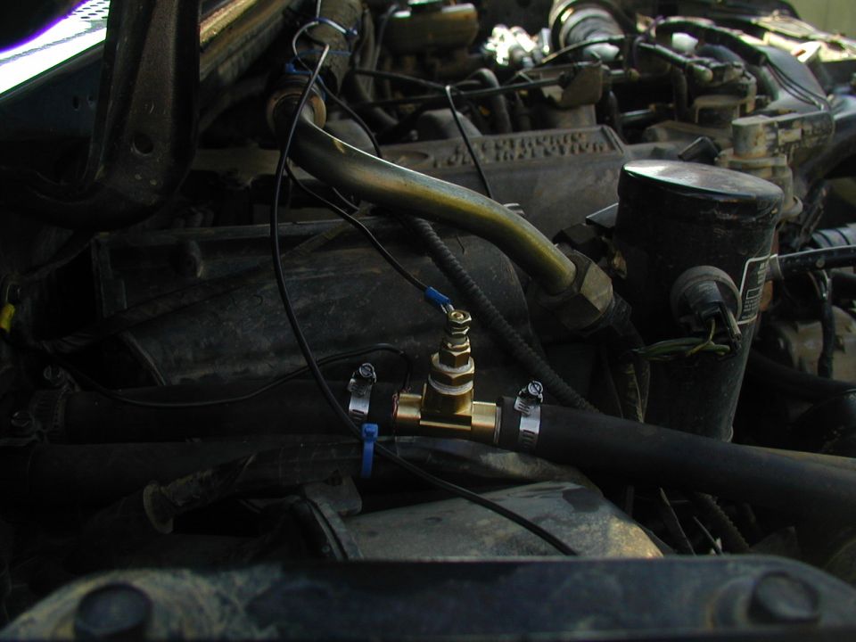 engine bay with a brass valve installed on a hose, wires connected