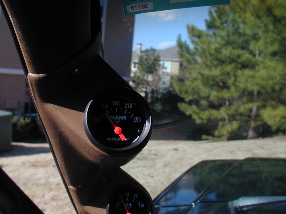 Dashboard gauges mounted on a brown A-pillar, with a transmission temperature gauge visible