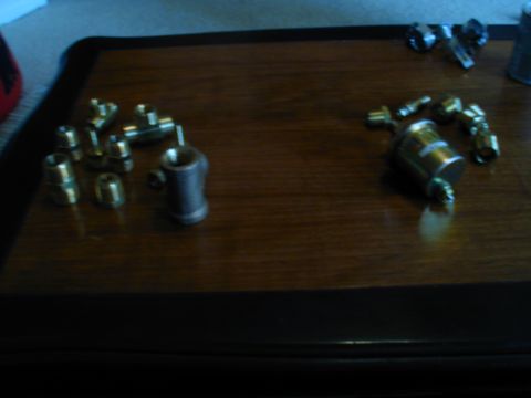 1988 Ford Bronco - Various brass fittings and gauges are laid out on a wooden surface.