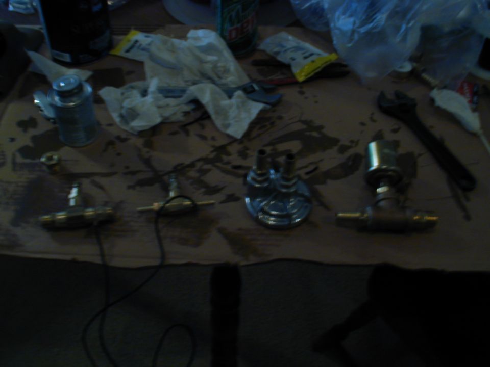 Several brass fittings and gauges laid out on a surface with tools and rags