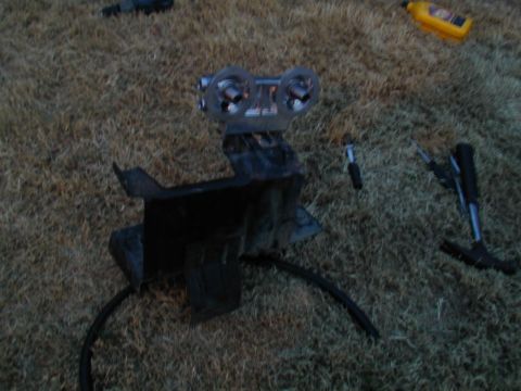 1988 Ford Bronco - A disassembled gauge cluster with two circular gauges is shown on the ground, along with tools and a bottle of fluid.