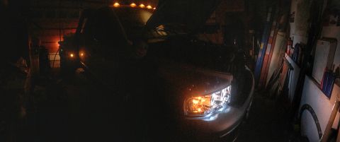 2004 Dodge 3500 - Headlights illuminate a truck in a dimly lit garage with its hood open.