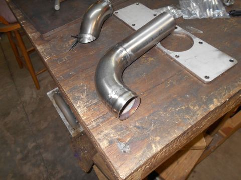 1992 Ford Bronco - Custom exhaust pipe and mounting plate shown on a wooden workbench.