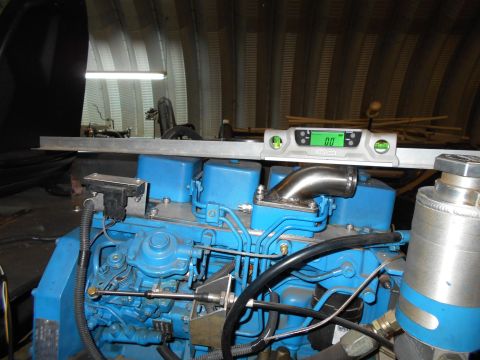 1992 Ford Bronco - A digital level is placed on top of a blue engine block in a workshop setting.
