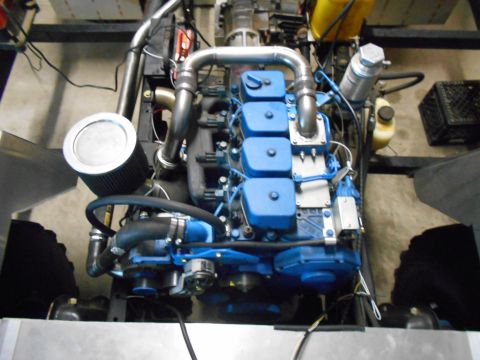 1992 Ford Bronco - Close-up view of a blue engine with silver exhaust components and a black air filter.