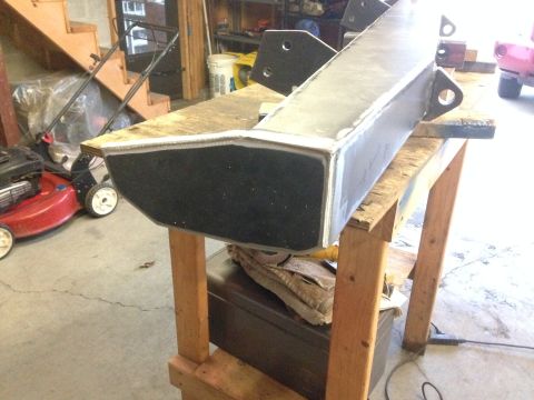 1979 Ford Bronco - A custom-fabricated bumper sits on a wooden stand in a garage setting.
