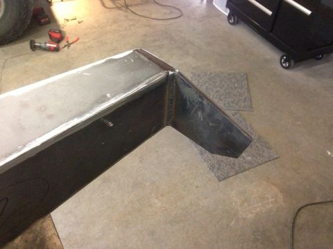 1979 Ford Bronco - A custom-fabricated steel bumper section is shown on a workshop floor, with tools and a toolbox in the background.
