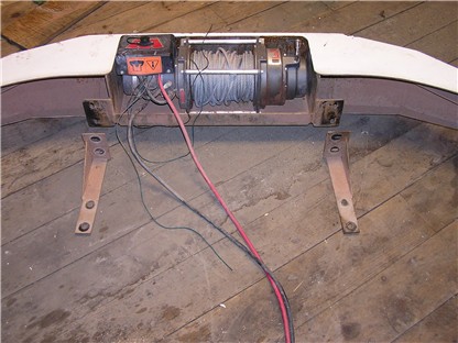 1993 Ford Bronco - A white winch bumper with a winch and wiring is shown on a wooden floor.