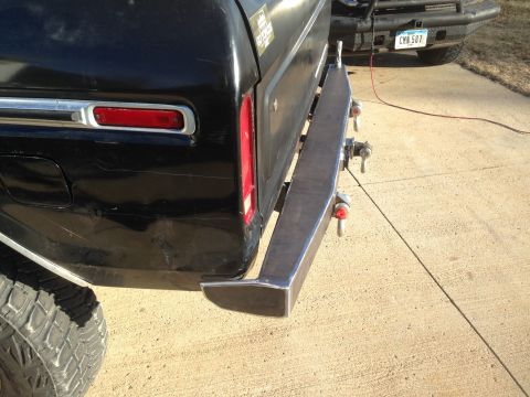 1979 Ford Bronco - The rear of a black 1979 Ford Bronco shows a custom fabricated bumper with tow hooks, and another vehicle is visible behind it.