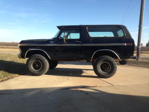 1979 Ford Bronco - This lifted Ford Bronco is parked on a concrete driveway under a clear blue sky.