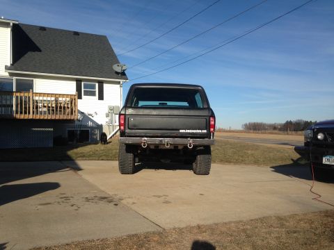 1979 Ford Bronco - A black Ford Bronco is parked in a driveway next to a house, with another vehicle visible on the right.