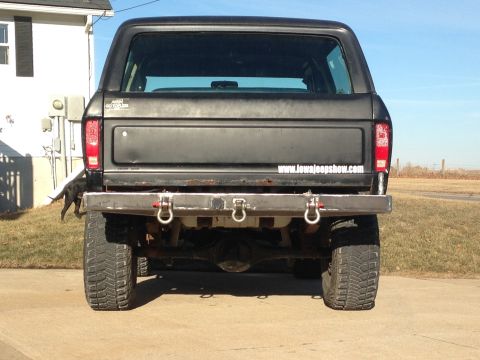 1979 Ford Bronco - The rear of a black Ford Bronco is shown with a custom bumper and large off-road tires.