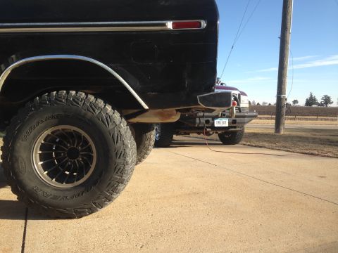 1979 Ford Bronco - Rear view of a 1979 Ford Bronco showing its bumper and tire, with another vehicle visible.