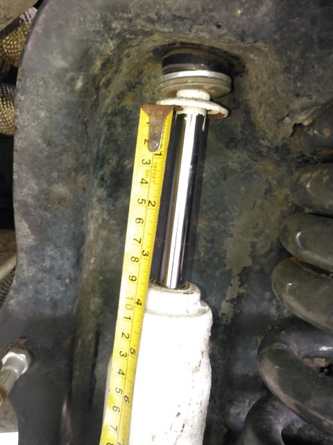 1996 Ford Bronco - Close-up of a shock absorber being measured, showing suspension parts and a tape measure.
