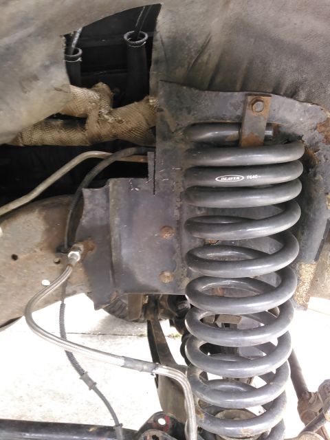1996 Ford Bronco - Close-up of a vehicle's suspension system, showing a coil spring and its mounting bracket.