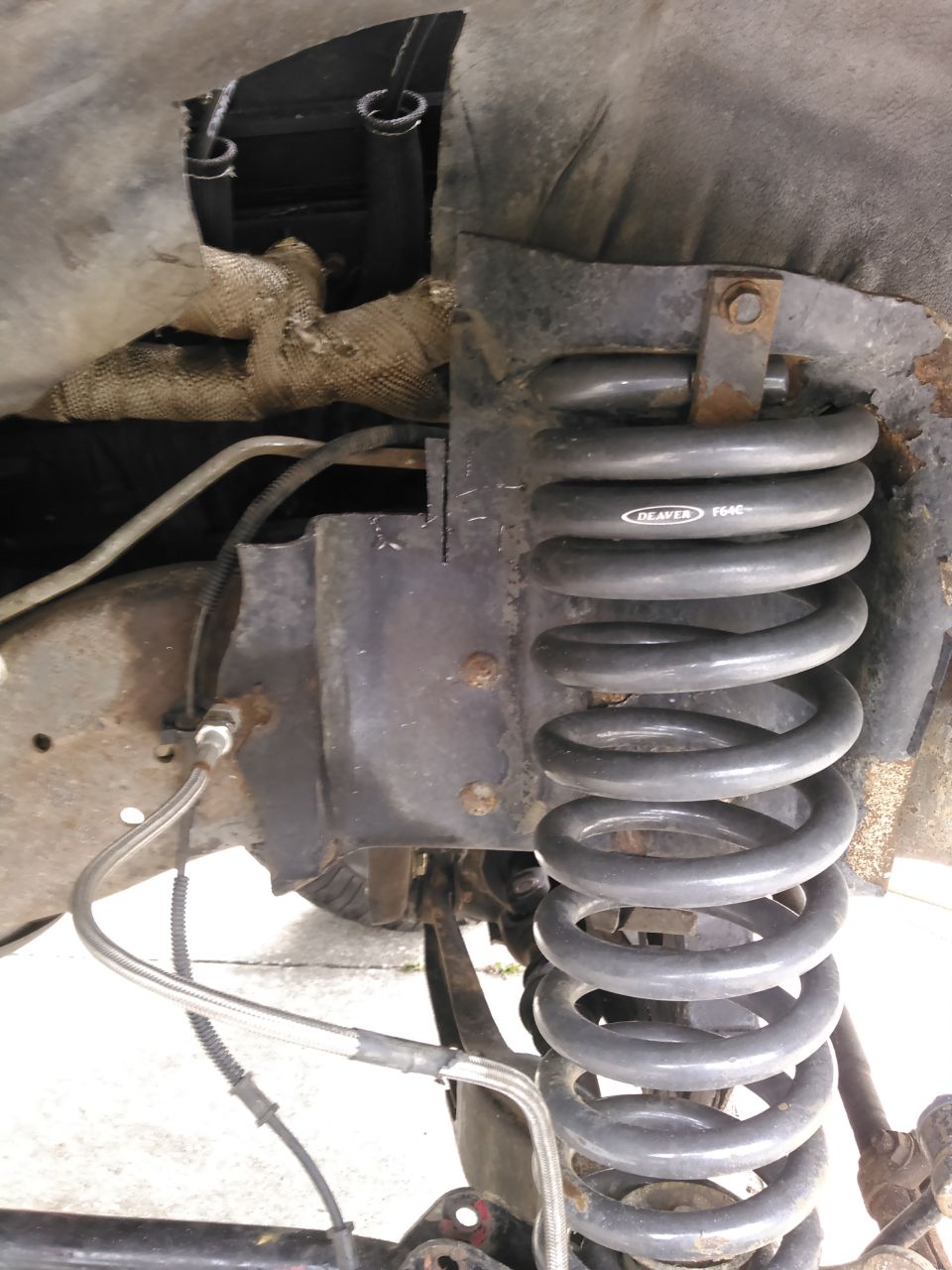 Coil spring with 'DEAVER 9640' text, attached to a rusty shock tower