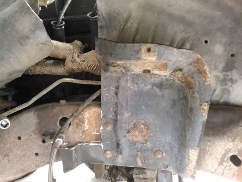 1996 Ford Bronco - Close-up view of a rusted shock tower and exhaust pipe with heat wrap, showing signs of wear and tear.