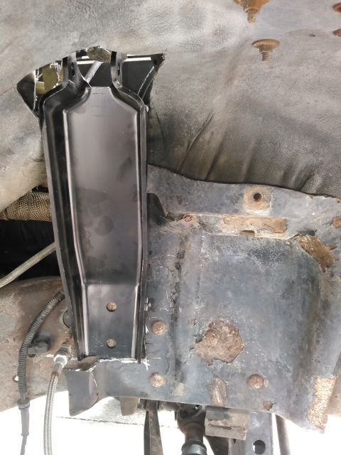1996 Ford Bronco - A black metal bracket is installed on the rusty frame of a vehicle, likely a 1996 Ford Bronco, with a cut-out in the wheel well liner above…