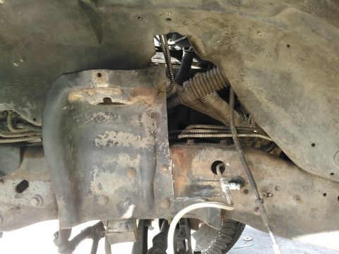 1996 Ford Bronco - This is a close-up, low-angle view of the undercarriage of a vehicle, focusing on the frame and suspension components. The metal parts are…