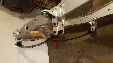 1994 Ford Bronco - A silver-painted vehicle frame is shown, with a leaf spring suspension system attached to the rear. The frame appears to be part of a resto…