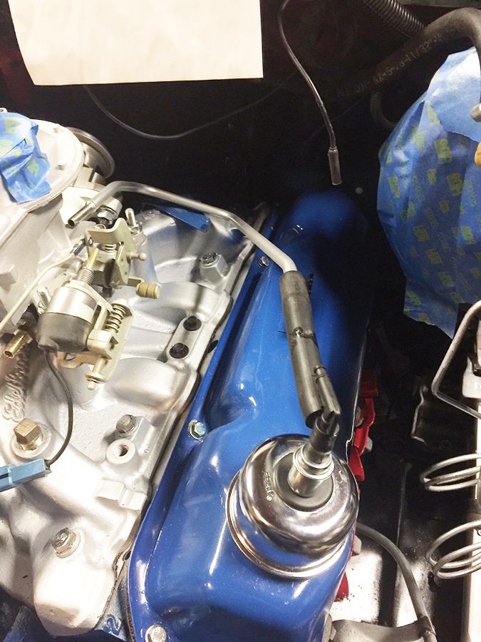 Close-up of a blue valve cover on a vehicle engine with a spark plug wire.